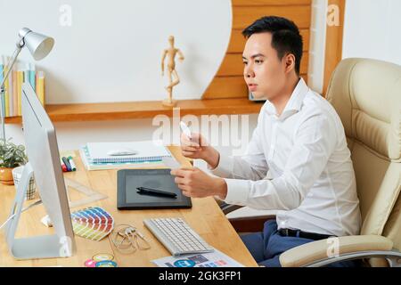 Pensive young UI designer choosing perfect icons for new application or website he is working on Stock Photo