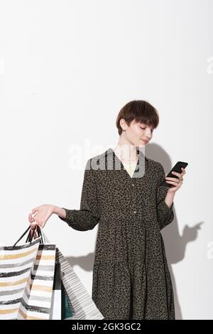 Young woman with shopping bags using her mobile phone to buy clothes online isolated on mobile phone Stock Photo