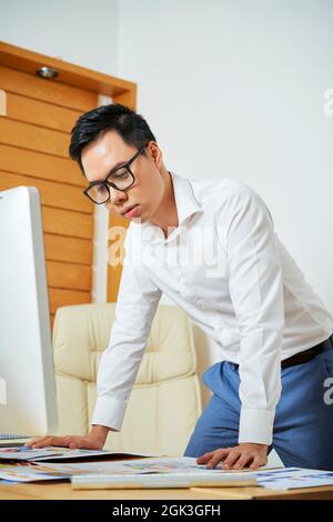 UI designer leaning on his office desk when working on perfect mobile application layout Stock Photo