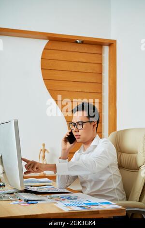 Graphic designer talking on phone with customer discussing changes that have to be done Stock Photo