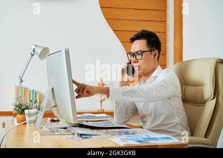 Professional UI designer talking on phone with client discussing color change and font size with customer Stock Photo