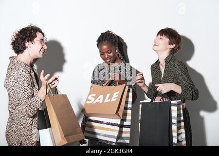Group of young friends with shopping bags looking excited and happy after shopping while standing against the white background Stock Photo