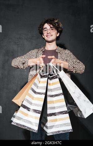 Portrait of young shopaholic holding shopping bags against the black background Stock Photo