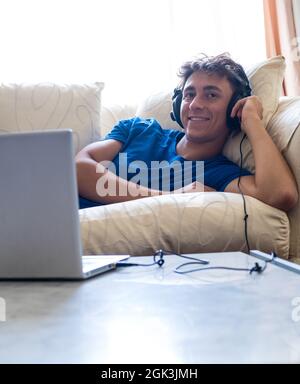 Young boy on sofa watching movies with laptop computer - young people with  technology - modern lifestyle with online courses and school stock photo Stock Photo