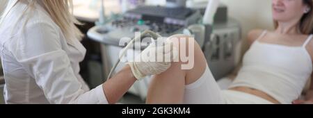 Doctor performs ultrasound examination of patient leg Stock Photo