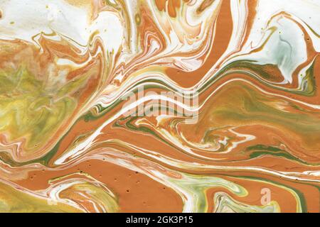 Acrylic texture made in liquid pour technique. Background in earthy colors with gold glittering paints. Stock Photo