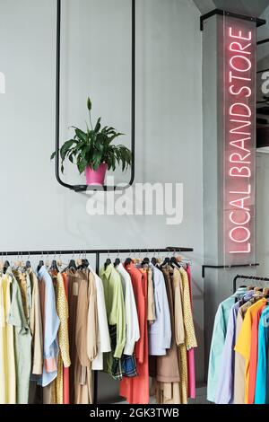 Image of local clothing store with fashion clothes and illuminated sign on the wall Stock Photo