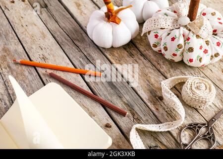 Cozy pumpkins. Autumn decoration with handmade colorful fabric pumpkins and planner or book on white wooden background. Fall vibes. Thanksgiving decor Stock Photo