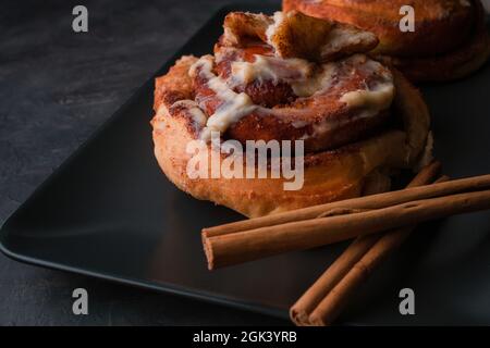 Cinnamon rolls on black plate with dark background. Stock Photo