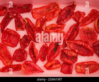 Sun dried tomatoes with dry spices on a pink oven dish Stock Photo
