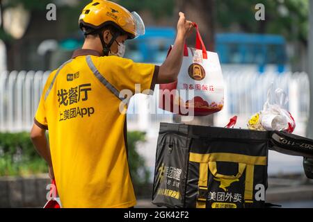 A Meituan courier picks up food from a restaurant and loads it on an electric scooter in Beijing, China. 13-Sep-2021 Stock Photo