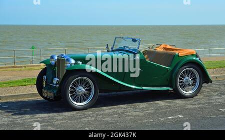 Classic Green MG parked on coastal road with the ocean in the background. Stock Photo