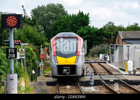 GreaterAnglia passenger train running across level crossings Woodbridge Suffolk England Stock Photo