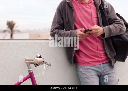 unrecognizable young man with his bicycle using phone, concept of technology and urban lifestyle, copy space for text Stock Photo