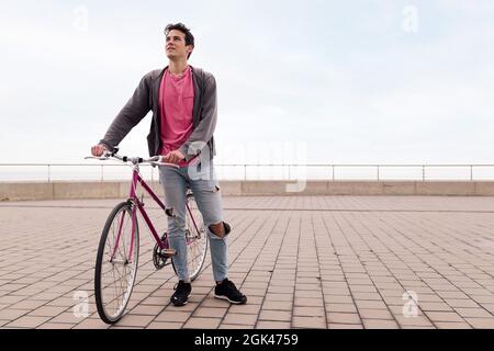 handsome young student holding a vintage bike, concept of sustainable transportation and urban lifestyle, copy space for text Stock Photo