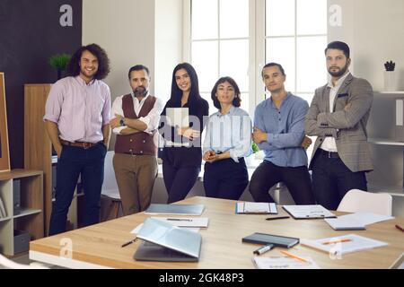 Team of happy successful business professionals standing by window in modern office Stock Photo