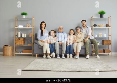 Portrait of three generations of one family sitting at home on sofa in living room. Stock Photo