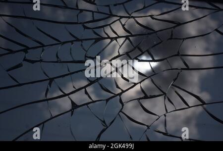 Broken glass with cracks on blue sky background. Close up view of broken glass texture Stock Photo