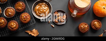 Autumn Breakfast. Homemade Pumpkin Spice Muffins with Salted Caramel and Pecan nuts, top view, banner. Fall seasonal baking concept. Stock Photo