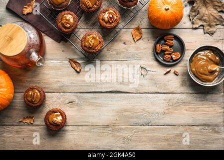 Autumn Breakfast. Homemade Pumpkin Spice Muffins with Pecan nuts and Tea on wooden table, top view, copy space. Fall seasonal baking concept. Stock Photo