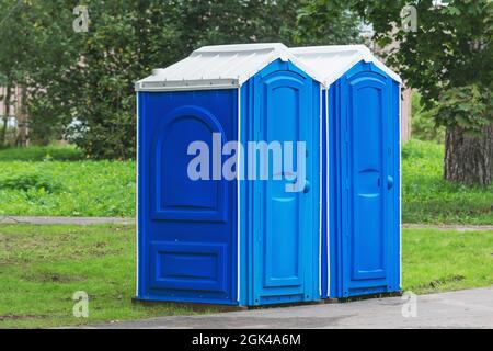 Two blue plastic toilet cabins. Public toilets in the city park. Stock Photo