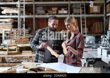 Two carpenters man and woman talking about design of products. Small business concept. Stock Photo