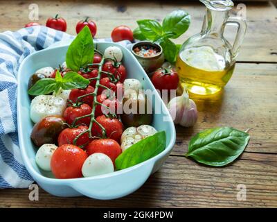 Fresh vegetable tomato, basil, mozzarella cheese for baking in the oven in ceramic dishes. cooking. Stock Photo