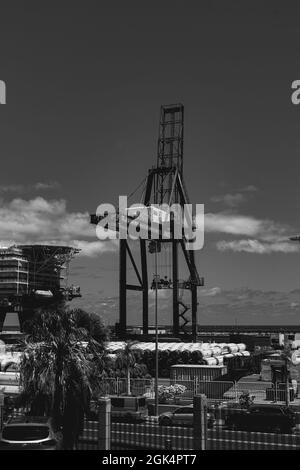 A vertical grayscale shot of a construction crane by an unfinished ...