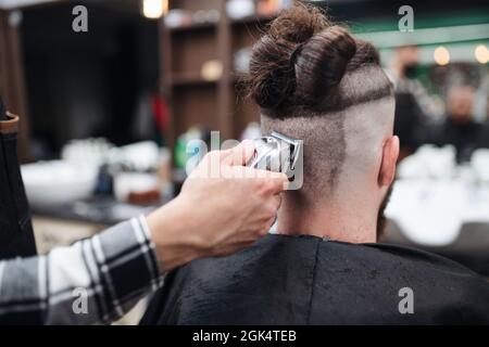 Rear view of man client visiting haidresser in barber shop. Stock Photo