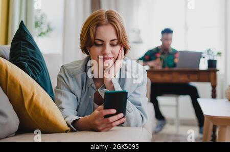 Young couple at home using digital divices, smartphone and laptop, social networks concept. Stock Photo
