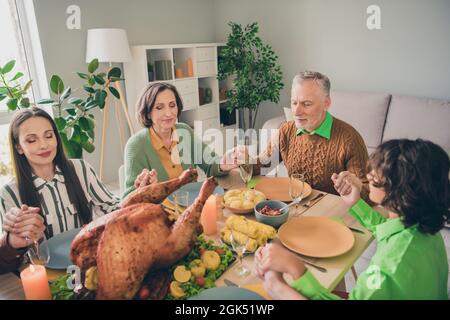 Portrait of adorable attractive family eating homemade festal dishes praying thanking for harvest autumn fall at home house Stock Photo