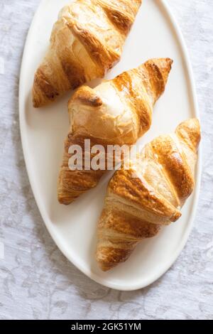 Three croissants on oval plate. Stock Photo