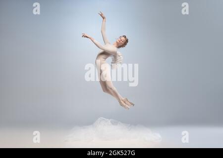 Young and graceful ballet dancer, ballerina dancing in image of angel with wings isolated on gray studio background. Art, motion, action, flexibility Stock Photo