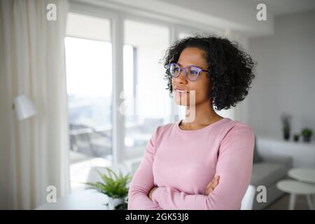 Portrait of happy mature woman indoors at home, looking aside. Stock Photo