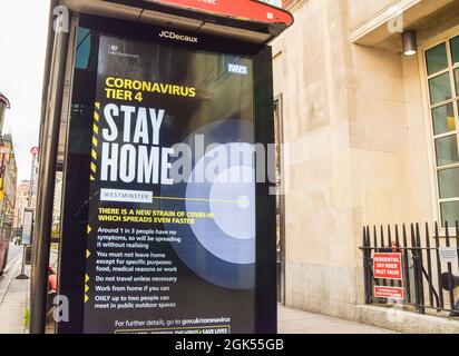 A 'Stay Home' bus stop sign on Charing Cross Road during the coronavirus lockdown. London, United Kingdom 24 December 2020. Stock Photo