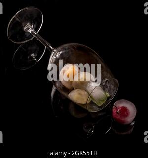 A glass in a horizontal position contains ice cubes with frozen fruit inside Stock Photo