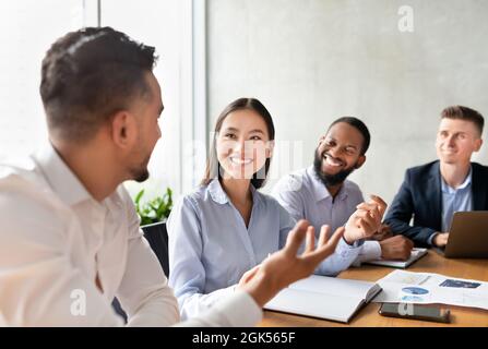 Business Meeting Concept. Young Multiethnic Team Discussing New Ideas Together In Office Stock Photo