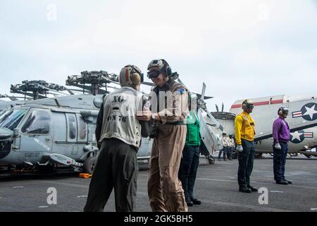 210806-N-WS494-1231 ARABIAN SEA (Aug 6, 2021) – Royal Australian Air Force Air Commodore Nathan Christie, Combined Air Operations Center (CAOC) director, is greeted by Capt. Matthew Ventimiglia, executive officer of aircraft carrier USS Ronald Reagan (CVN 76), during a visit to the ship in the Arabian Sea, Aug. 6. Ronald Reagan is deployed to the U.S. 5th Fleet area of operations in support of naval operations to ensure maritime stability and security in the Central Region, connecting the Mediterranean and Pacific through the western Indian Ocean and three strategic choke points. Stock Photo