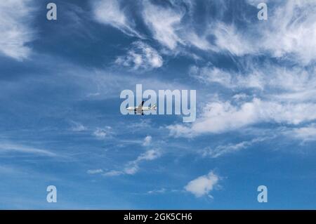 Plane Flying In Blue Sky With Clouds Stock Photo