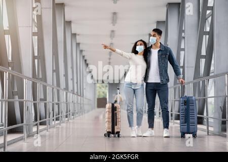 Young Middle Eastern Spouses Wearing Medical Masks Waiting With Suitcases In Airport Stock Photo