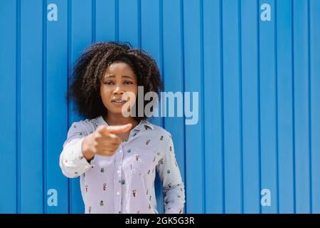 Afro woman looking serious and pointing at the camera indicating something while standing outdoors. Stock Photo