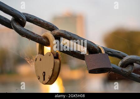 Rusty lovers locks on a chain on a bridge, lovers locks on a bridge chain Stock Photo