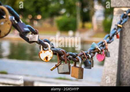 Rusty lovers locks on a chain on a bridge, lovers locks on a bridge chain Stock Photo
