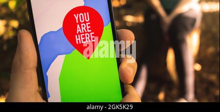 Man using maps on mobile phone for navigation in the forest. Outdoor hiking and travel banner concept Stock Photo