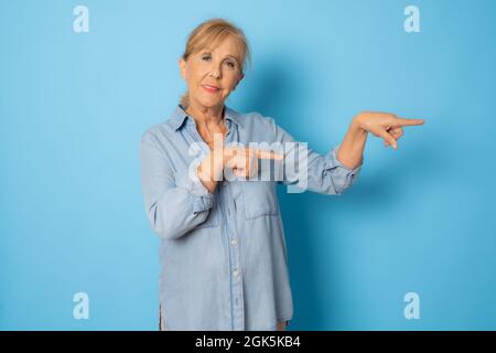 Senior woman wearing casual clothes smiling and looking at the camera pointing with two hands and fingers to the side. Stock Photo
