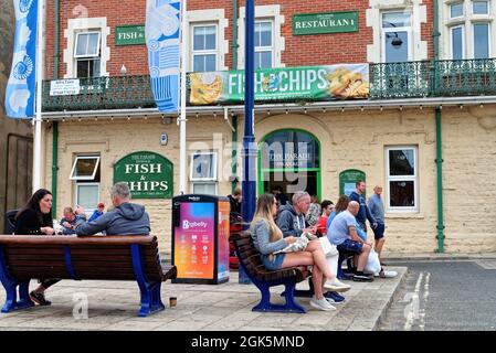 Holidaymakers enjoying fish and chips outside the Parade fish and chip restaurant in The Square, Swanage Dorset England UK Stock Photo