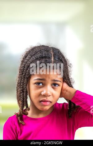 Little African-American girl with hearing problem on light background ...