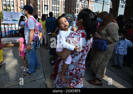 Families line up to drop off their children for in-person learning as New York City Public Schools reopen, in the Queens borough of New York, September 13, 2021. New York City Public schools system, which has been closed since March 2020 and is the largest in the United States with over a one million children, returns to full in-class teaching with no the remote learning option; teachers are expected to be vaccinated against COVID-19, and students will have to wear protective face masks while in class. (Photo by Anthony Behar/Sipa USA) Stock Photo