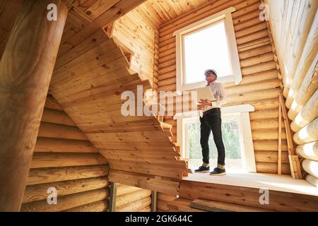 Engineer looking up the stairs while making notes in laptop Stock Photo