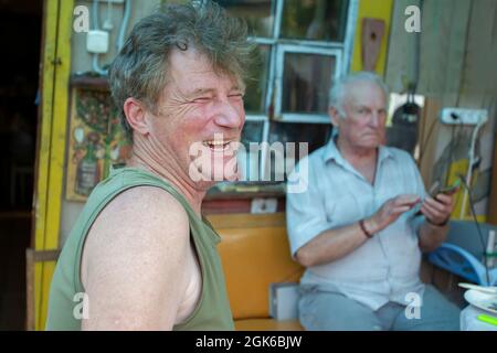 An adult son laughs merrily against the background of an elderly old man's father. Father and son. Stock Photo